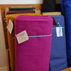 Purple fabric roll with tags on a rack with other fabric colors in the background