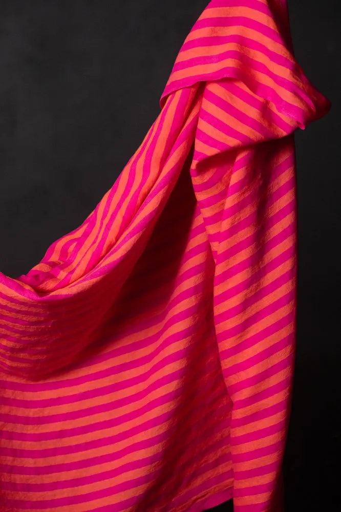 A swatch of neon orange and fuchsia striped linen fabric against a black background.