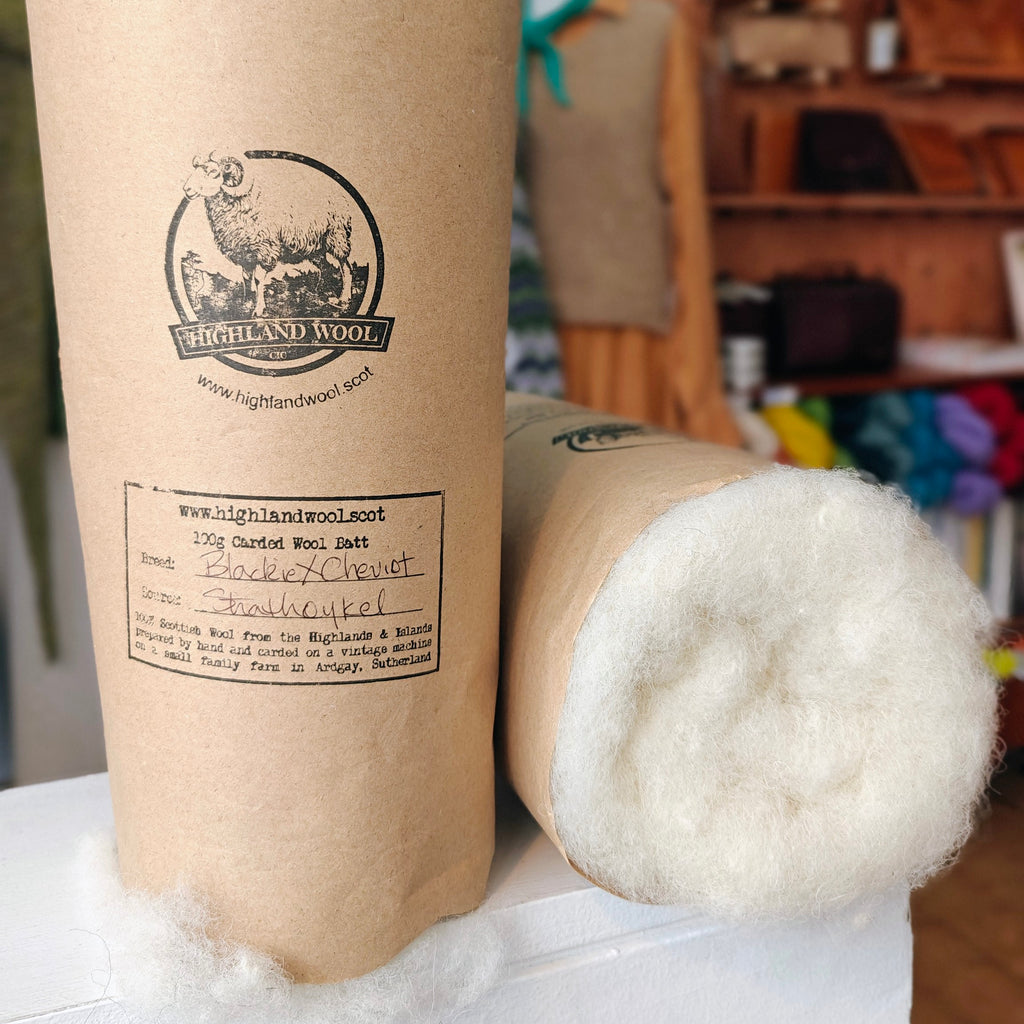 Carded wool batts with Highland Wool branding on cardboard tubes.