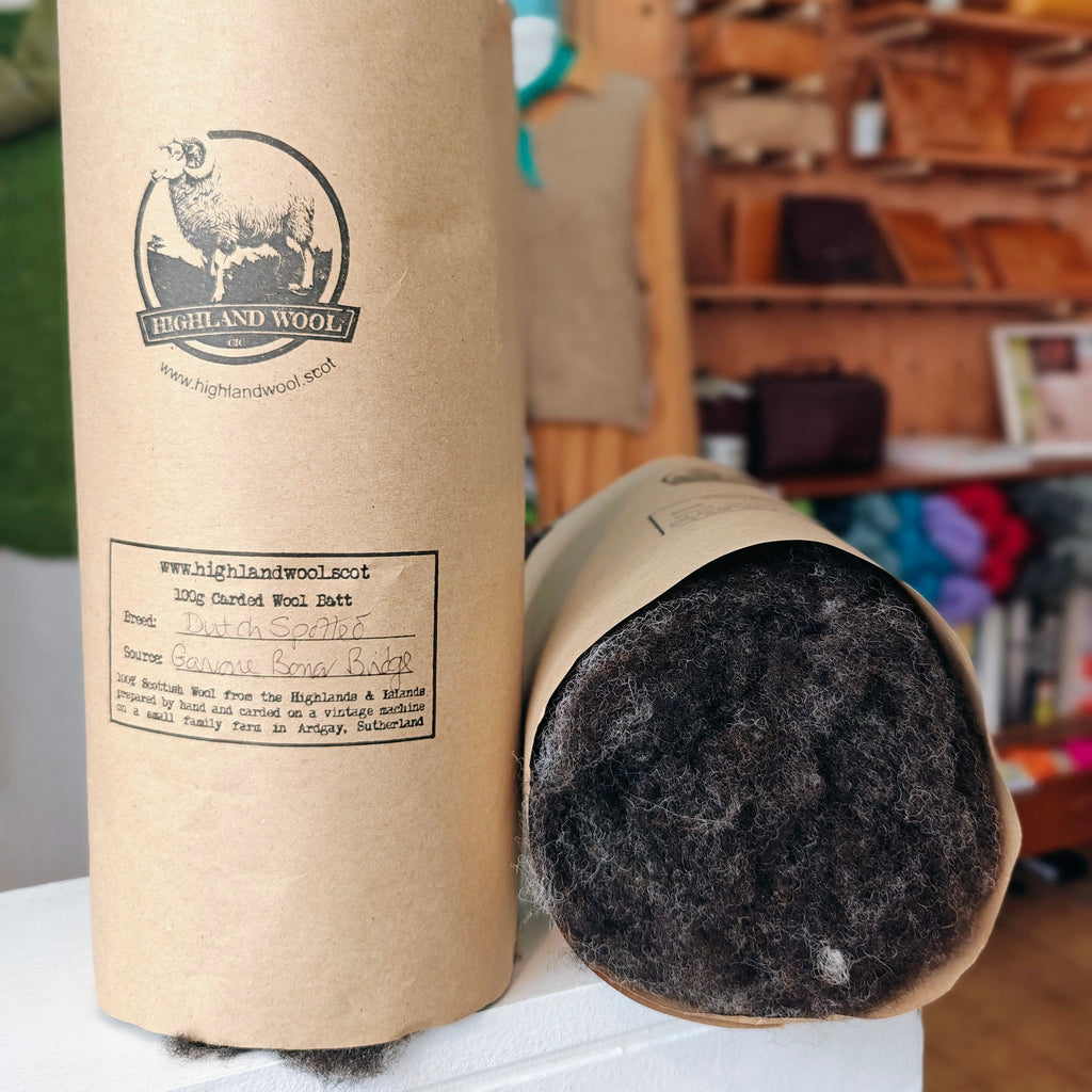 Cardboard tube packaging with Highland Wool branding, containing gray wool batting.