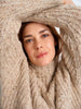 Woman peeking through a large beige knitted sweater