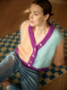 Woman wearing a colorful knitted cardigan sitting on a patterned rug.