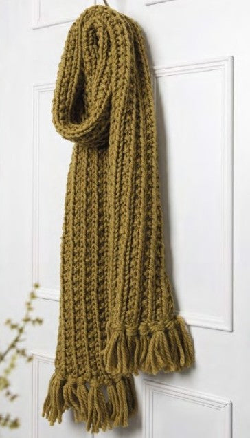 Knitted mustard yellow scarf with tassels on a white door