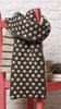 Knitted scarf with a pattern draped over a red chair against a white brick wall.