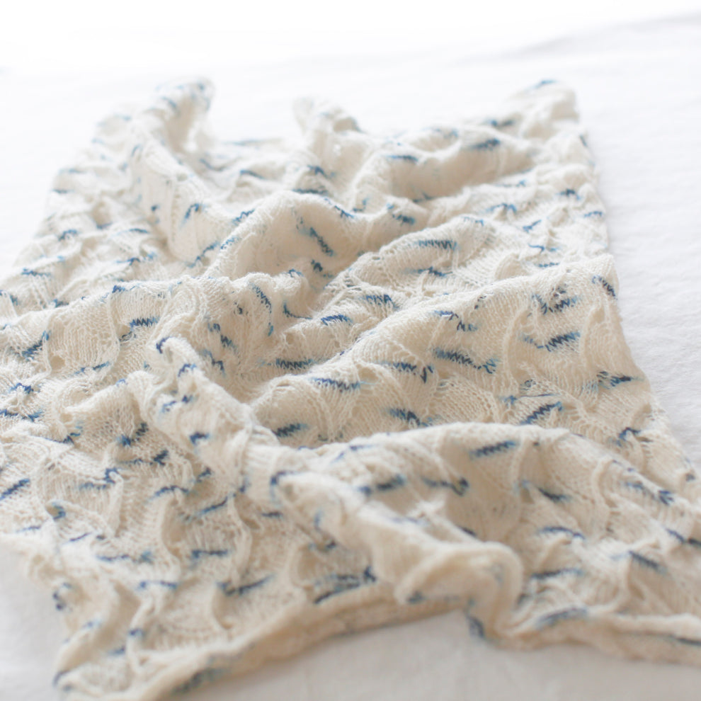 Folded beige fabric with blue specks on a white background