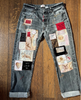 Denim jeans with various patches on a wooden surface