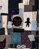 A close-up of a patchwork quilt featuring various fabric squares in dark blue, beige, black, and white, decorated with silhouettes, patterns, and the handwritten text 'Let love in.'.