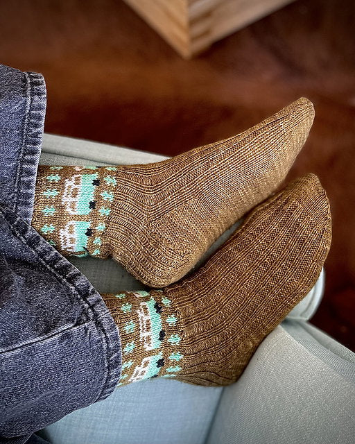Brown patterned socks worn by a person sitting on a couch.