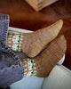Brown patterned socks worn by a person sitting on a couch.