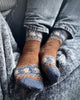 Person wearing patterned brown and blue socks on a gray surface