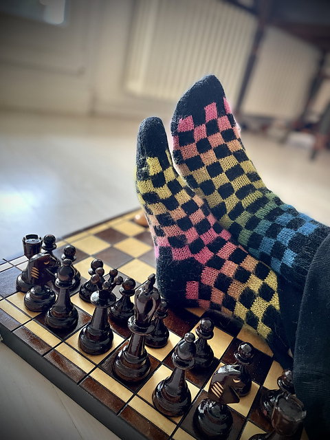 Colorful checkered sock on a chessboard with chess pieces.