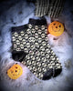 Pair of black and white patterned socks with Halloween-themed decorations on a textured surface.