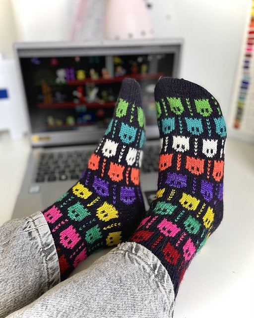 Colorful patterned socks being worn with a laptop in the background