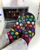 Colorful patterned socks being worn with a laptop in the background