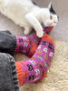 Cat playing with colorful socks on a carpeted floor