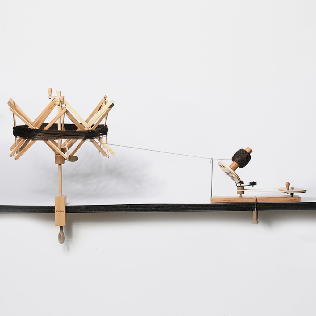 Wooden umbrella swift and ball winder winding a skein of yarn.