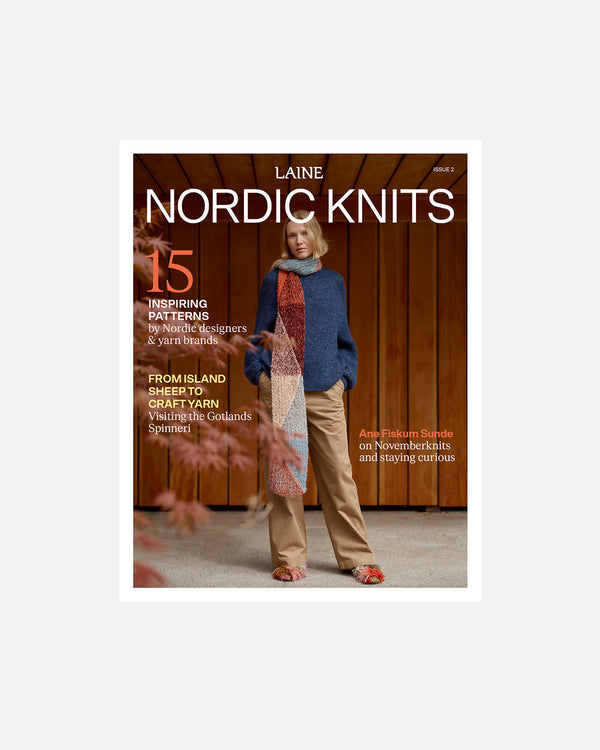 A book or magazine cover titled 'Laine Nordic Knits' featuring a woman standing in front of a wooden wall, wearing a blue sweater, tan pants, and a long multicolored scarf. The cover includes text about patterns and knitting inspiration.