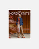 A book or magazine cover titled 'Laine Nordic Knits' featuring a woman standing in front of a wooden wall, wearing a blue sweater, tan pants, and a long multicolored scarf. The cover includes text about patterns and knitting inspiration.