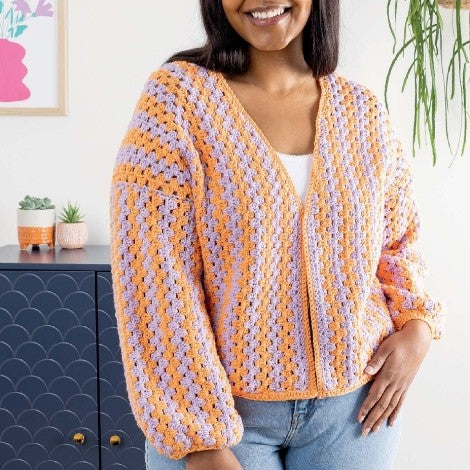 Woman wearing a colorful crochet cardigan in a home setting