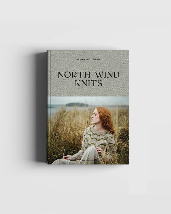 Book titled 'North Wind Knits' with a cover featuring a person in a knit sweater sitting in a field.