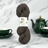 Ball of yarn with a label on a marble surface with tea set in the background