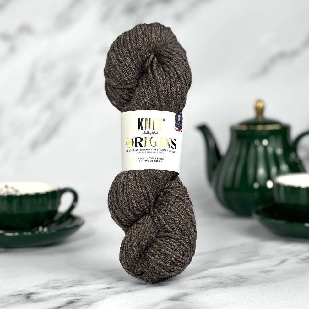 Ball of yarn with a label on a marble surface with tea set in the background
