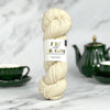 Ball of yarn with a label on a marble surface with tea set in the background