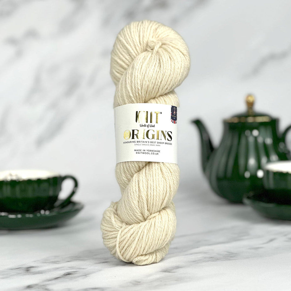 Ball of yarn with a label on a marble surface with tea set in the background