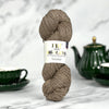 Ball of yarn with a label on a marble surface with tea set in the background