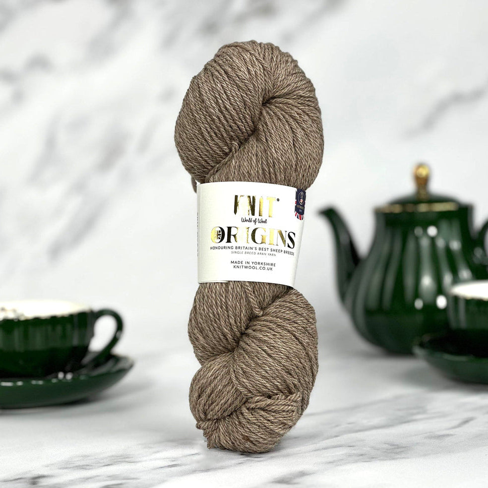 Ball of yarn with a label on a marble surface with tea set in the background