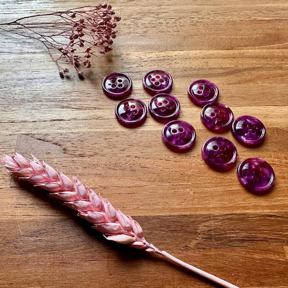 Purple buttons on a wooden surface with dried pink flowers