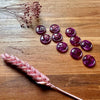 Purple buttons on a wooden surface with dried pink flowers