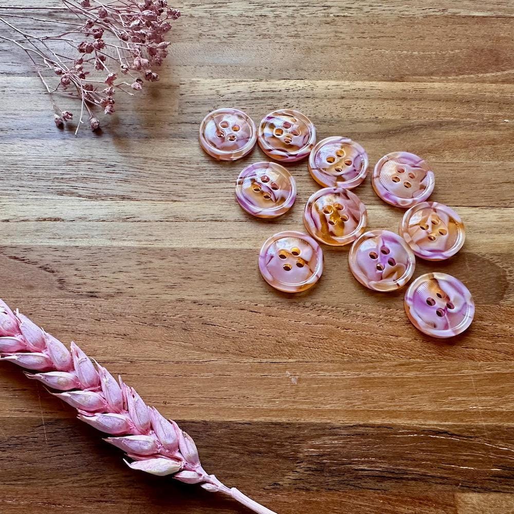 Pink buttons on a wooden surface with dried pink flowers