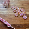 Pink buttons on a wooden surface with dried pink flowers