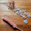 Set of decorative buttons on a wooden surface with dried pink flowers.