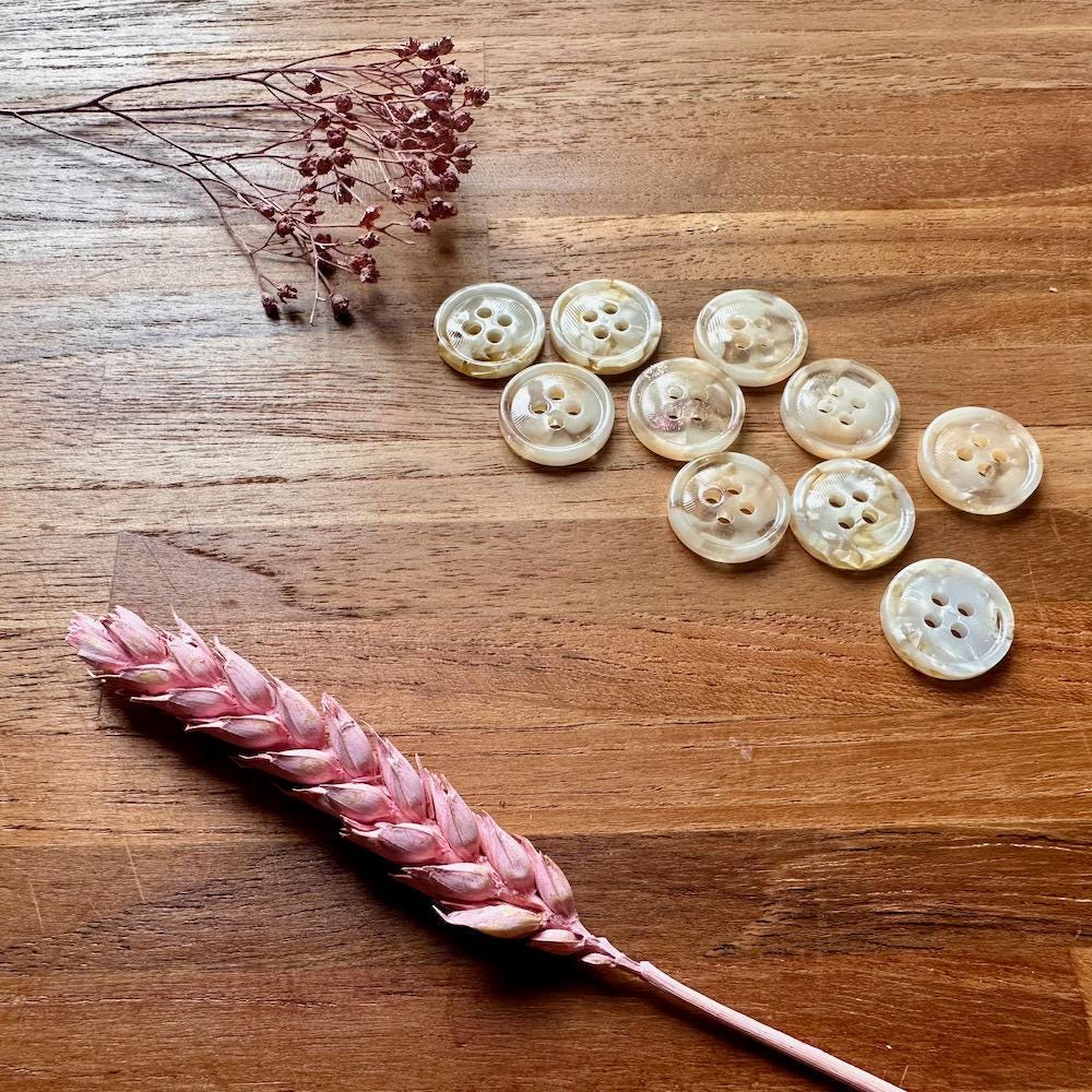 White buttons on a wooden surface with dried pink flowers