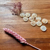 White buttons on a wooden surface with dried pink flowers