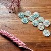 Light blue buttons on a wooden surface with pink dried flowers