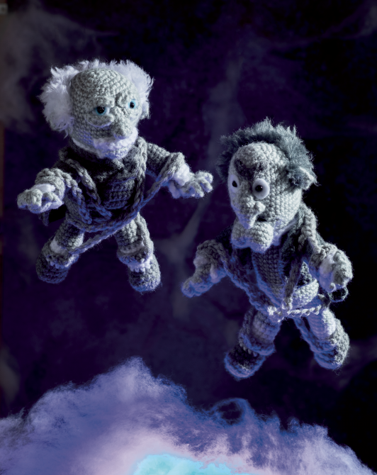 Two crocheted dork-like character dolls floating against a dark purple background with soft blue cloud-like shapes at the bottom.