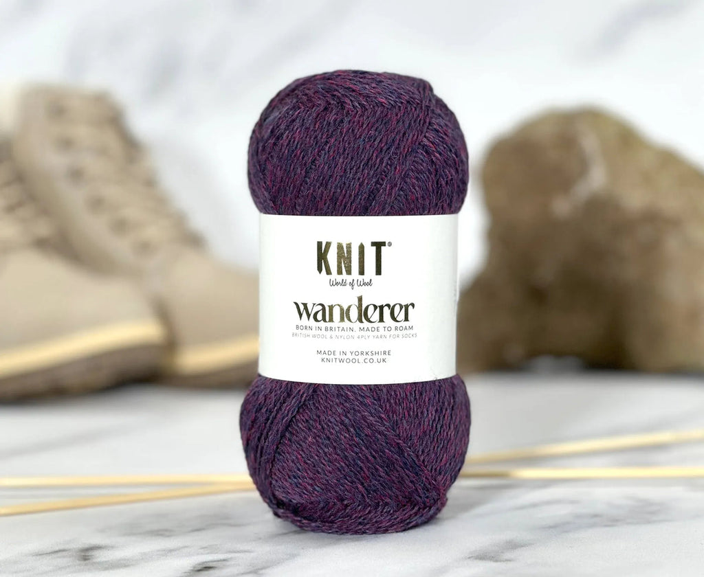 Ball of purple yarn with 'Knit Wanderer' label on a marble surface