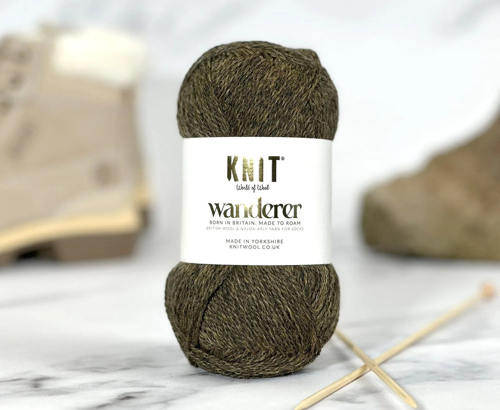 Ball of yarn with a label on a marble surface with knitting needles.