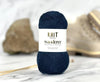 Navy blue yarn ball with 'Knit Wanderer' label on a marble surface
