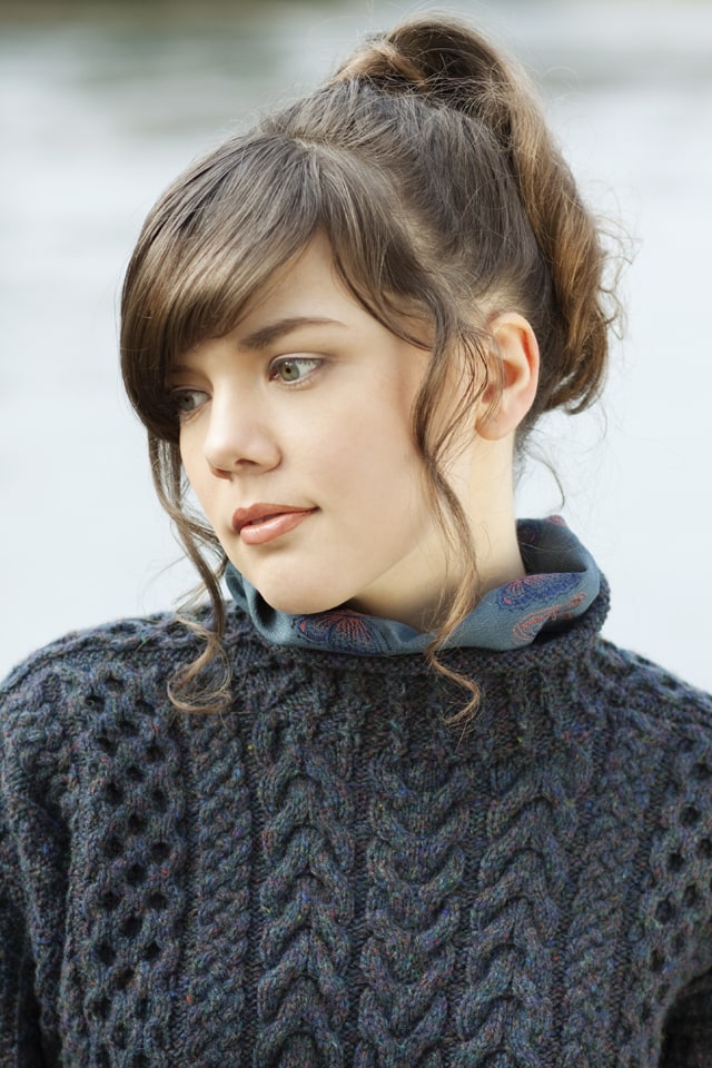 Woman wearing a dark blue knitted sweater with a blurred natural background