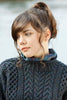 Woman wearing a dark blue knitted sweater with a blurred natural background