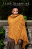 Woman wearing a mustard yellow textured shawl with fringes, standing outdoors.