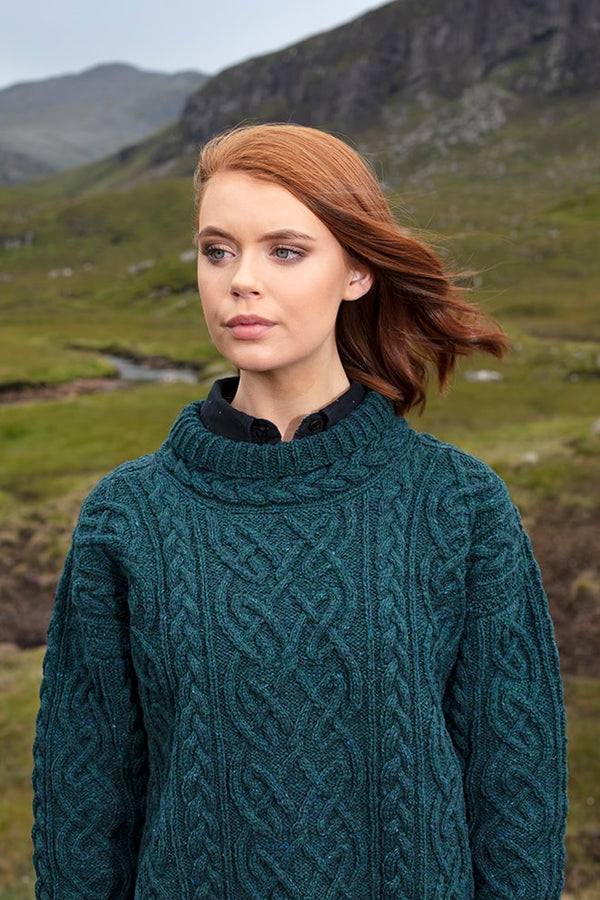 Woman wearing a teal cable knit sweater in a natural landscape