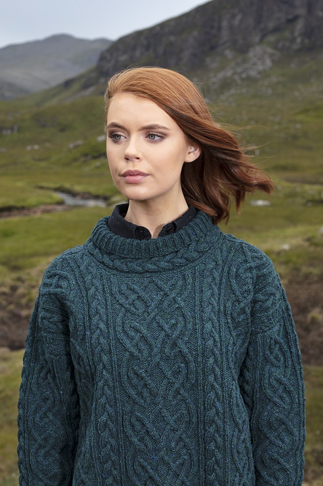 Woman wearing a teal cable knit sweater in a natural landscape