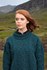 Woman wearing a teal cable knit sweater in a natural landscape