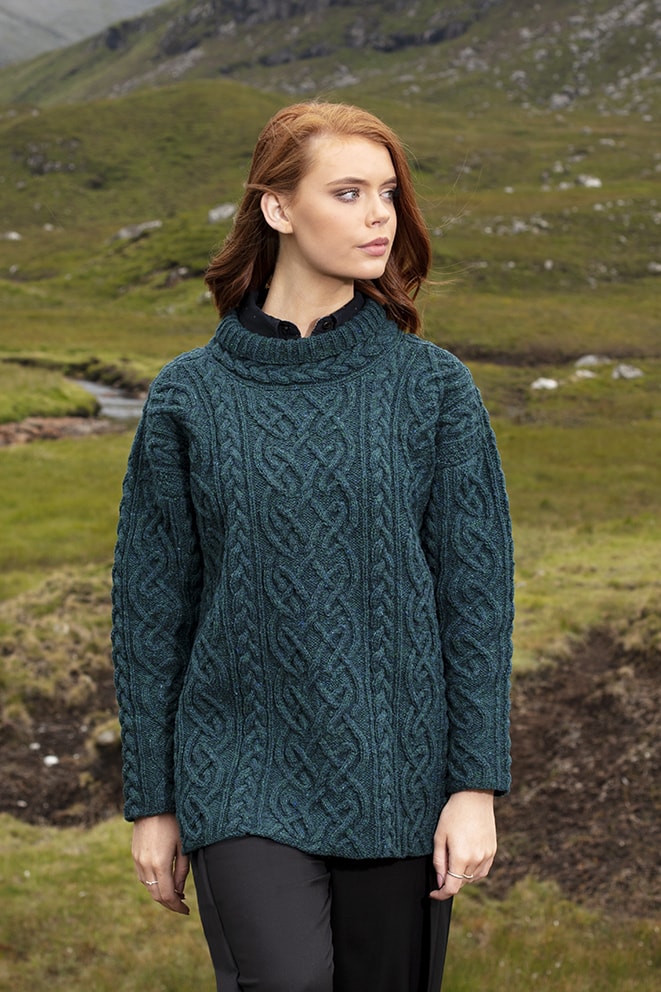 Woman wearing a teal cable knit sweater in a natural landscape