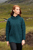 Woman wearing a teal cable knit sweater in a natural landscape